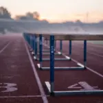 Des haies d'athlétisme sont alignées sur une piste de course marquée par des numéros au sol